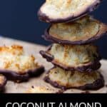 A tempting stack of almond macaroons dipped in rich chocolate sits on a wooden surface, with more coconut almond macaroons scattered nearby.