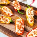 Vegetables filled with a creamy cheese mixture, topped with bacon bits, and beautifully arranged on a wooden serving board.