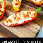 Stuffed Mini Peppers halved and filled with cream cheese, topped with crispy bacon bits, are arranged beautifully on a wooden board.
