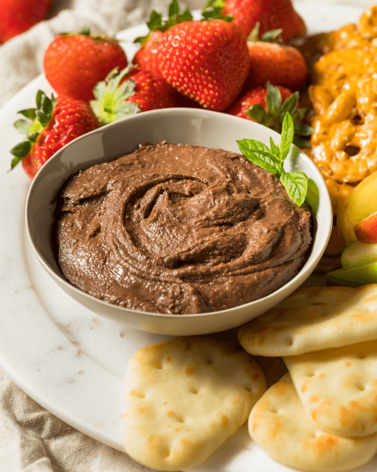 A platter of fruit and crackers with the chocolate hummus.