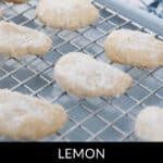 Several Lemon Cooler Cookies coated with powdered sugar are cooling on a metal rack, their zesty aroma filling the air.