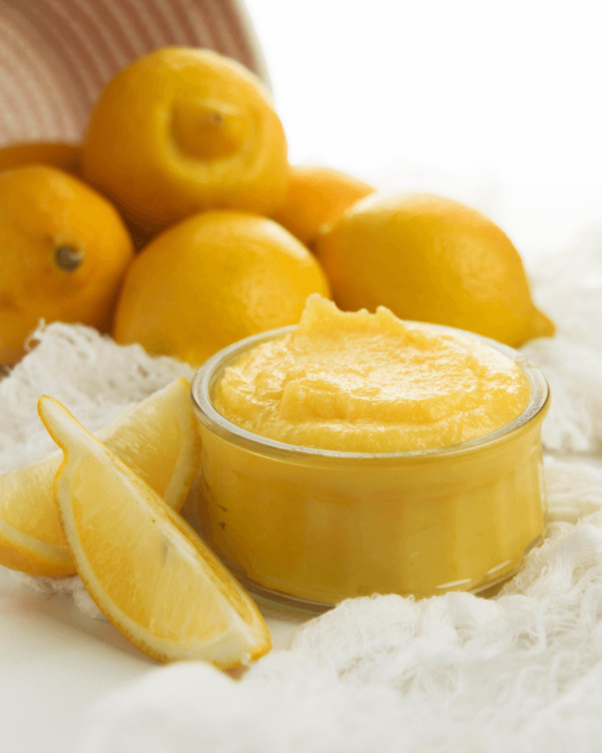 A pile of lemons with a bowl of the curd.
