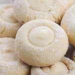 A close-up of several Lemon White Chocolate Cookies, dusted with powdered sugar and filled with creamy white centers.