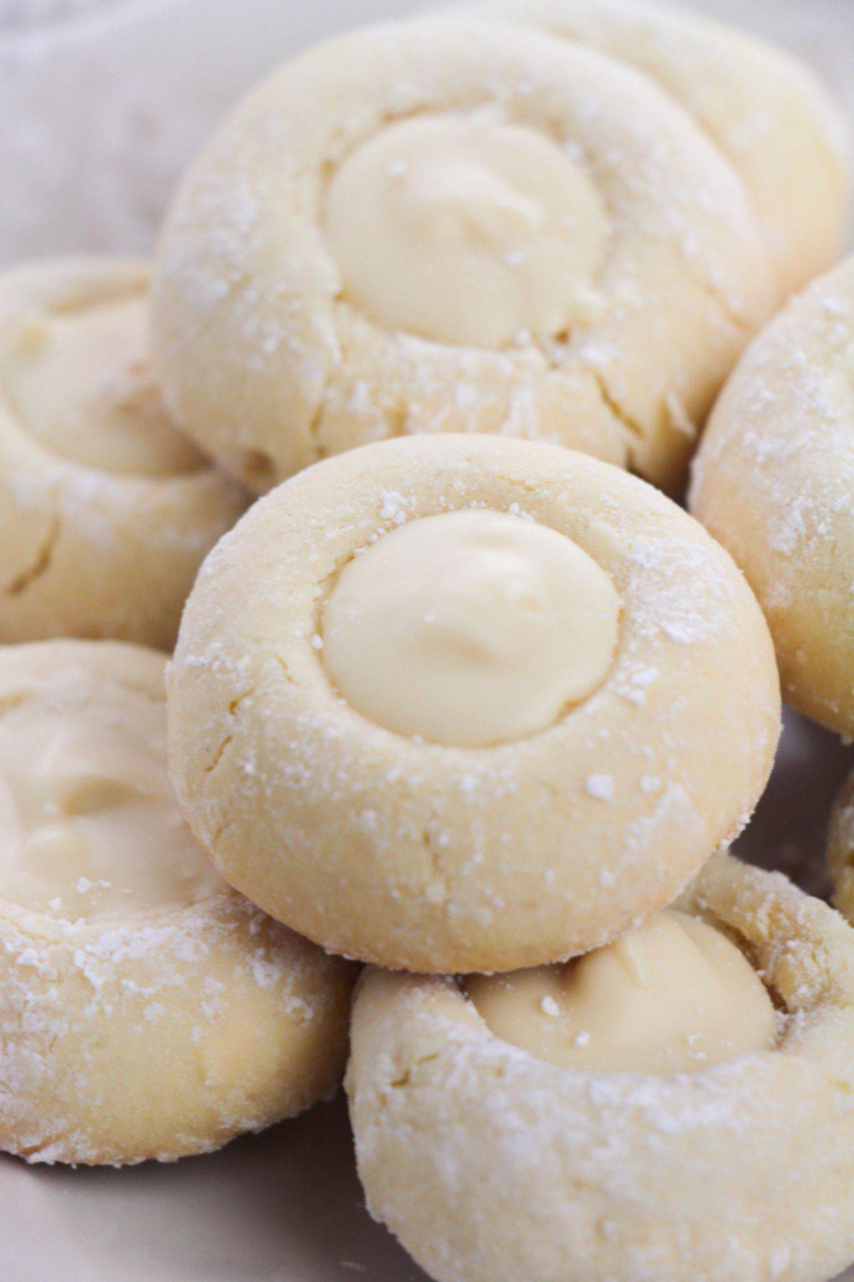 A close-up of several Lemon White Chocolate Cookies, dusted with powdered sugar and filled with creamy white centers.