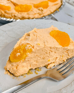 A slice of the orange cream pie on a white plate with a fork.