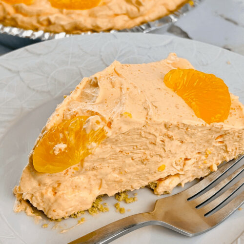 A slice of the orange cream pie on a white plate with a fork.