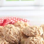 A group of No Bake Peanut Butter Oatmeal Cookies with a textured, oat-filled surface displayed on a wooden board in a bright kitchen setting.