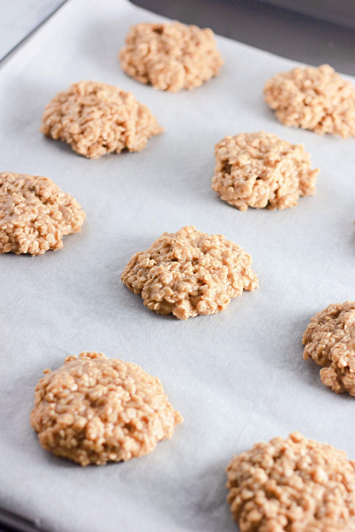 No Bake Peanut Butter Oatmeal Cookies spaced apart on a parchment-lined baking sheet, ready to set.