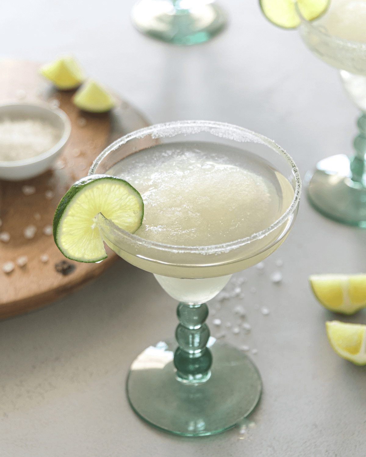 A glass full of the skinny margaritas recipe with slices of lime around it.