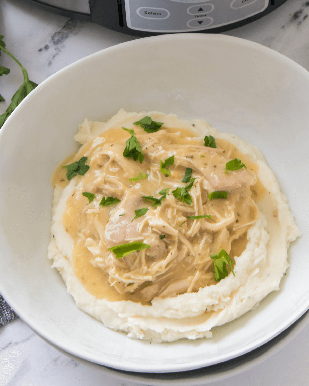 A bowl with mashed potatoes with the chicken and gravy on top.