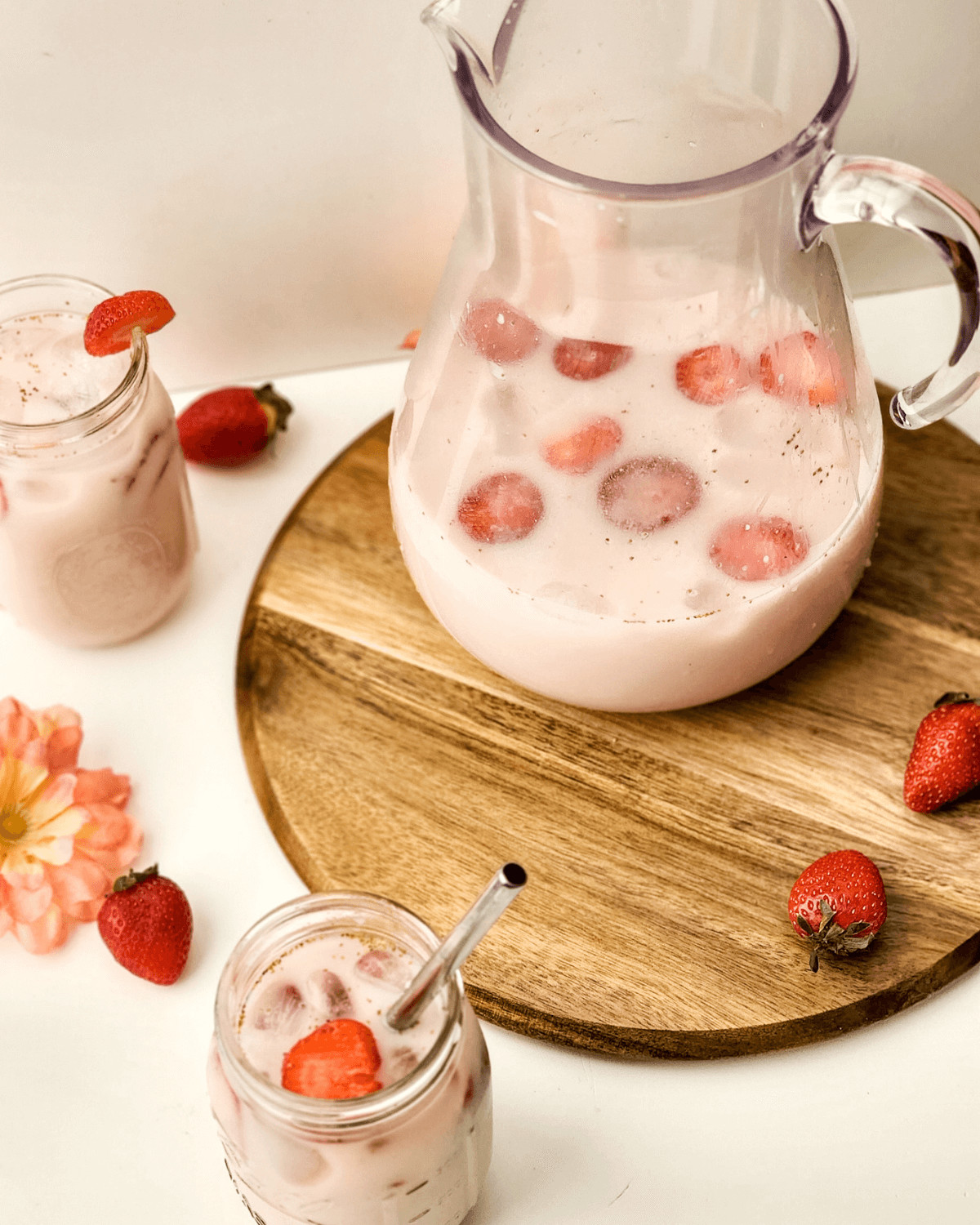 A pitcher and glasses of the finished drink with strawberries.