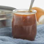 A jar of sauce with a spoon in it.