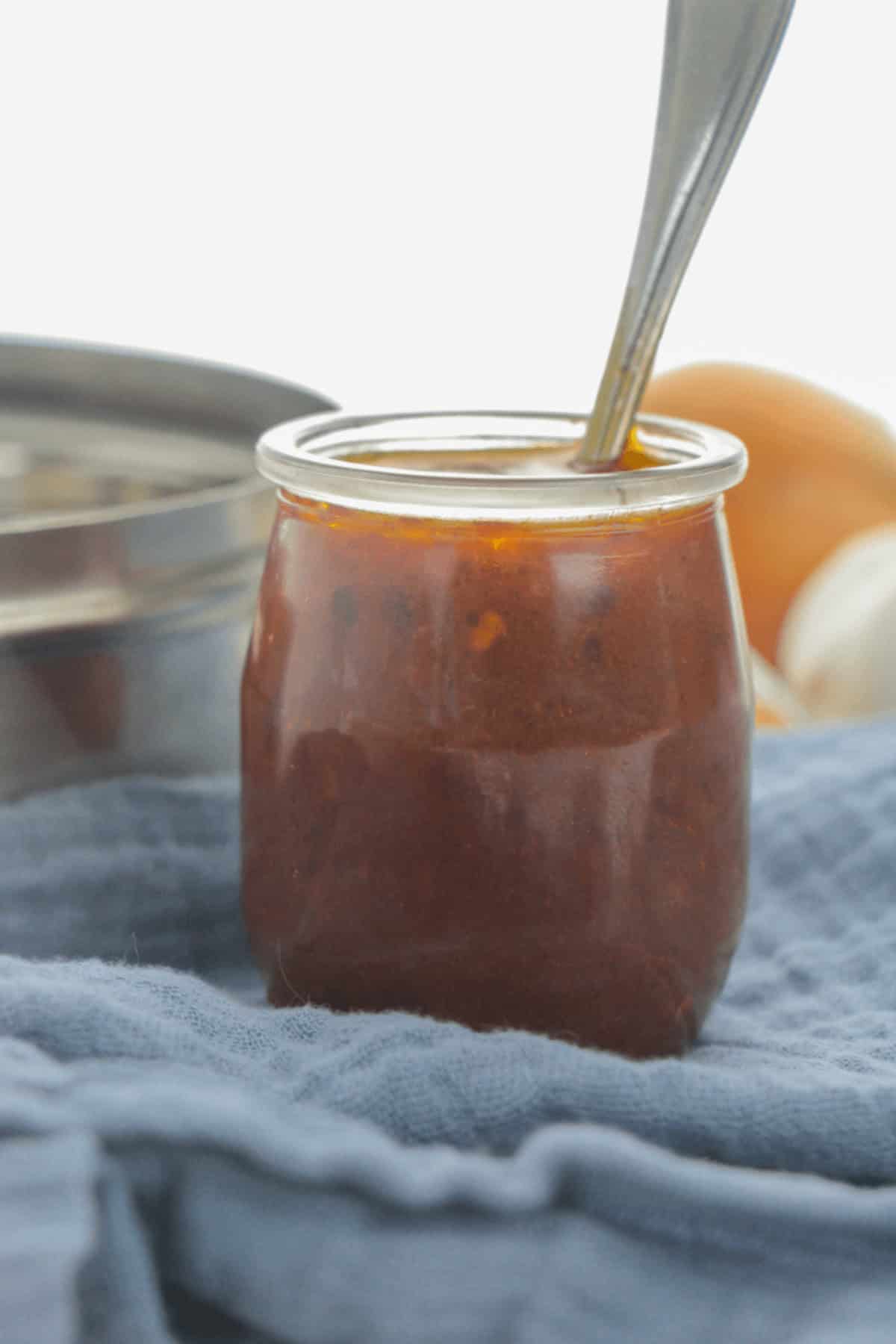 A jar of sauce with a spoon in it.