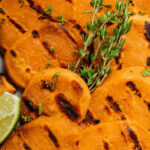 A closeup on the slices of sweet potatoes on the grill with grill marks.