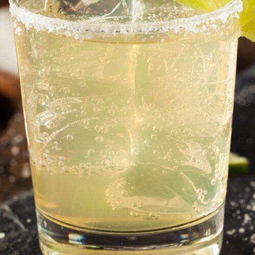 A glass of Classic Margarita with ice, a salted rim, and a lime wedge garnish.