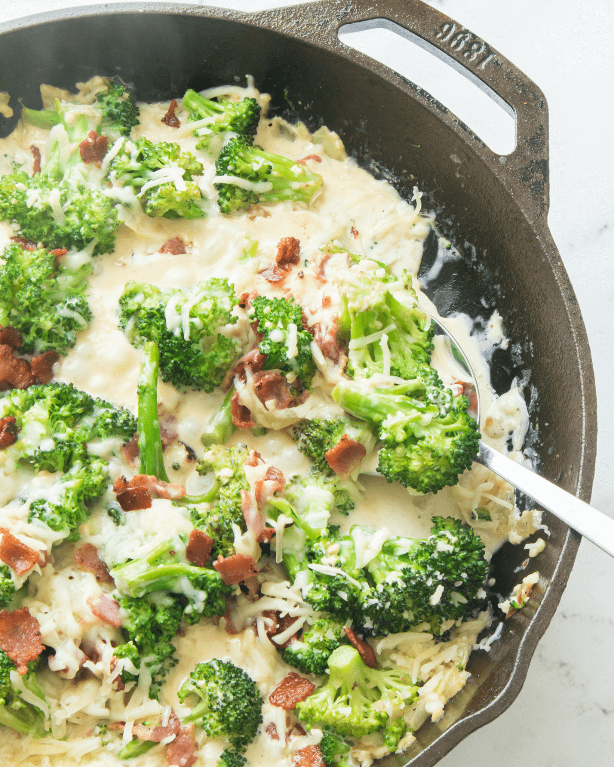 Creamy Broccoli in Parmesan Garlic Sauce in a cast iron pan.