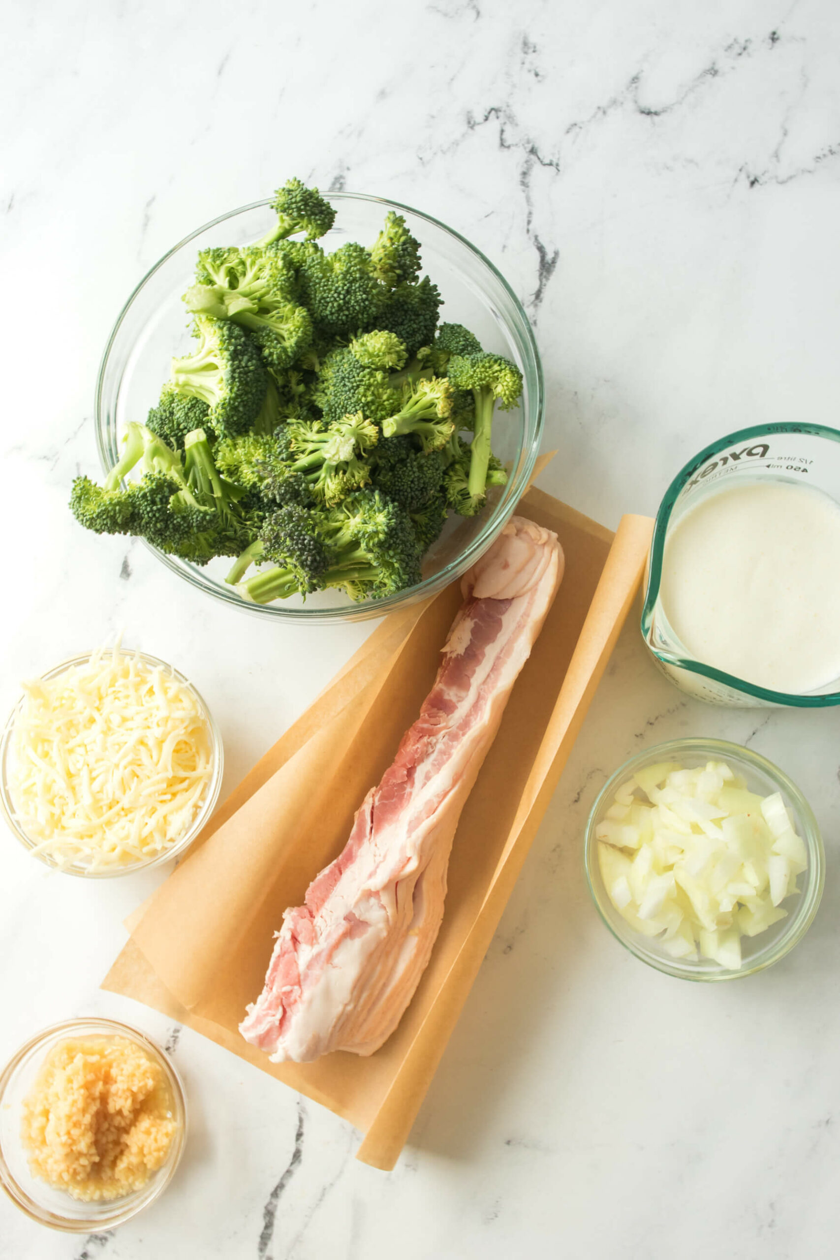 A bowl of fresh broccoli, cheese, bacon and cream.