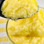 A close-up of a spoonful of yellow, creamy pudding taken from a bowl filled with the same dessert.