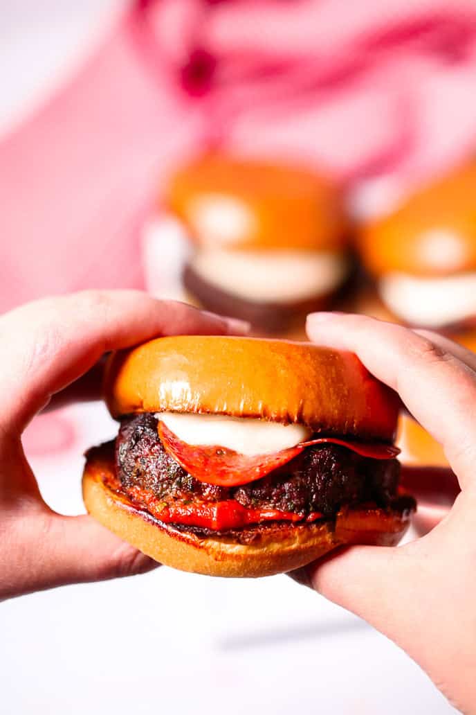 A hand holding a juicy hamburger.