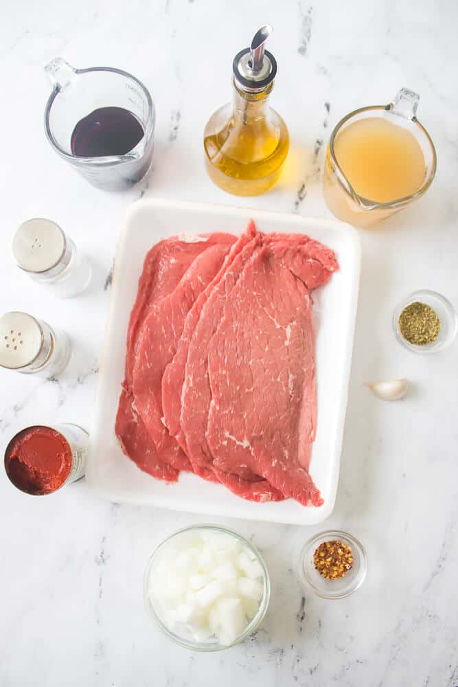 A dish of steak pizzaiola with sauce and seasoning.