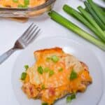 Scallions next to the dish of the prepared meal with a fork.
