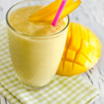 Mango beside a glass of the Bahama mama tropical smoothie.
