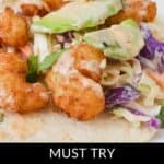 Savor the irresistible Boom Boom Shrimp tacos featuring crispy shrimp, creamy slaw, and fresh avocado slices, all wrapped in a warm tortilla. Text overlay reads: "Must Try Boom Boom Shrimp Tacos.