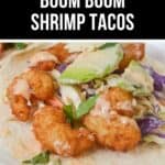 Close-up of a Boom Boom Shrimp taco, featuring crispy shrimp topped with slaw and drizzled sauce on a soft tortilla, highlighted by the text "Must Try Boom Boom Shrimp Tacos.