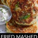 A plate of golden-brown Fried Mashed Potato Cakes garnished with fresh herbs, served with a side of tangy sour cream.