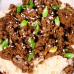A Beef Bulgogi Bowl featuring a plate of white rice, topped with seasoned ground beef, and garnished with green onions and sesame seeds.