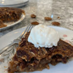 A slice of the no corn syrup pecan pie with whip cream on top.