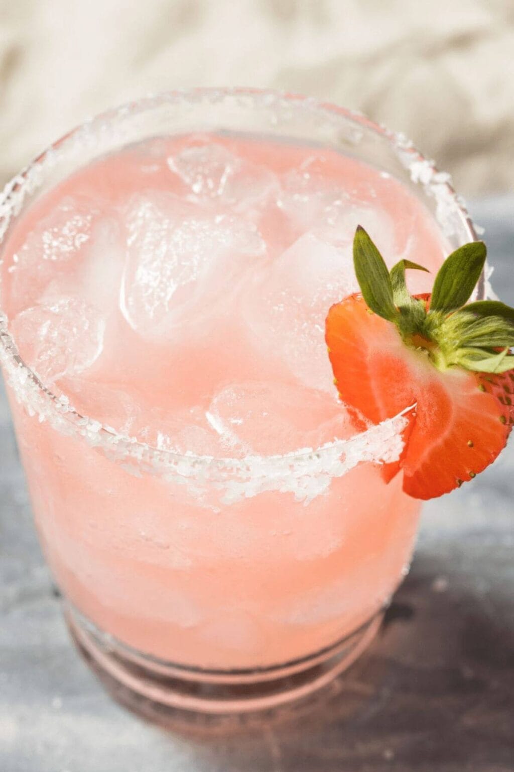 A Strawberry margarita in a clear glass on the rocks.