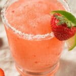 A clear glass with a salt rim and fresh fruit on top.