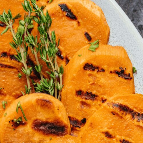 Sprigs of herbs on top of the sweet potato rounds.