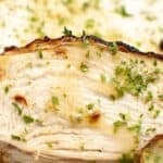 Close-up of a sliced, cooked chicken breast garnished with chopped herbs on a white plate—perfect inspiration for preparing Air Fryer Turkey Breast with similar flavors and presentation.