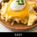 A wooden bowl holds a cheesy baked pierogi casserole, topped with melted cheese, sour cream, and fresh chives. Text reads: "Easy Baked Pierogi Casserole Delight.