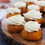 Cake Mix Pumpkin Spice Cookies with swirls of white frosting are arranged on a wooden serving platter.