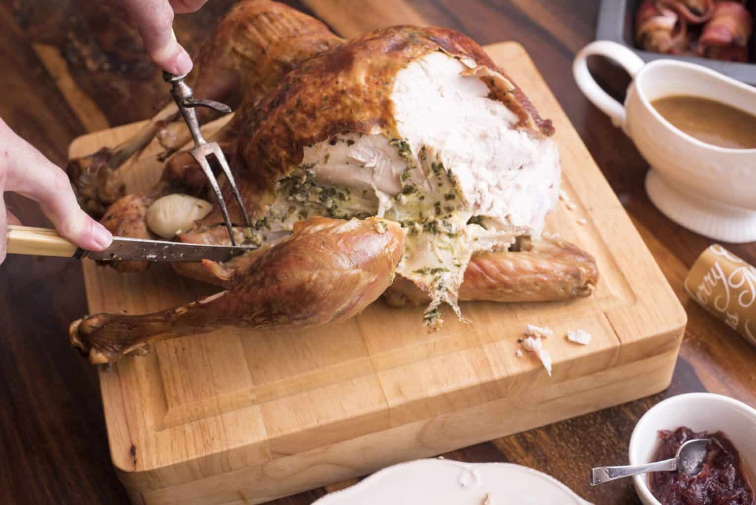 Carving a turkey by removing the leg and wing. 