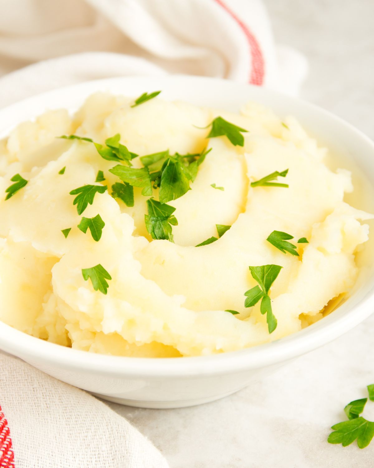 Creamy and fluffy side in a white bowl topped with fresh herbs.