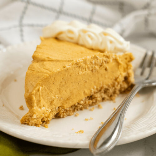 A white dish of pumpkin pie with gingersnap crust.
