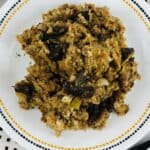 A plate of Crock Pot Stuffing with visible chunks of mushrooms and herbs, served on a white dish with a decorative border.