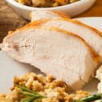 Crock Pot green beans on a white plate, with extra stuffing in a dish in the background.