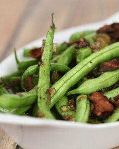 A close up on the green beans with bacon and onion.