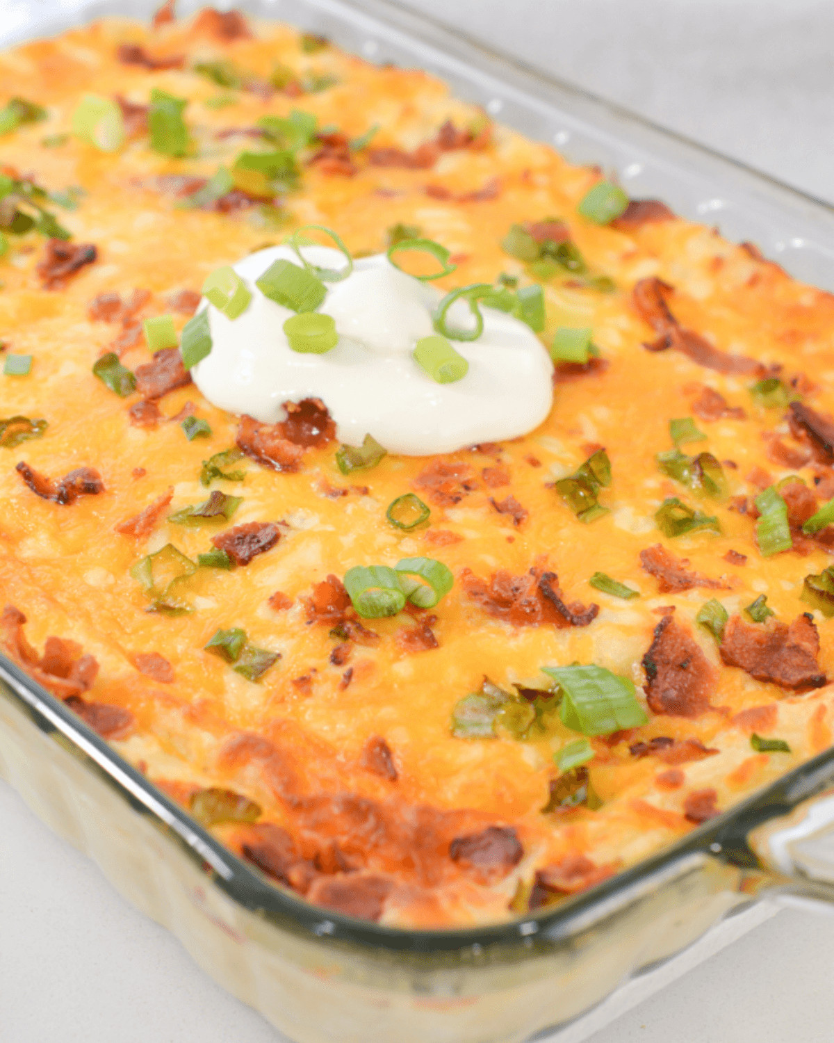 A casserole with sour cream and shopped onions on top.
