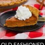 A slice of Old Fashioned Pumpkin Pie with whipped cream sits on a black plate, with a fork and a whole pie in the background on a red and white checkered tablecloth.