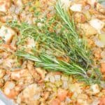Baking dish filled with the thanksgiving side and garnished with fresh rosemary and thyme sprigs.
