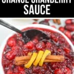 A bowl of Orange Cranberry Sauce topped with a cinnamon stick and orange peel, with a spoon resting in the bowl.