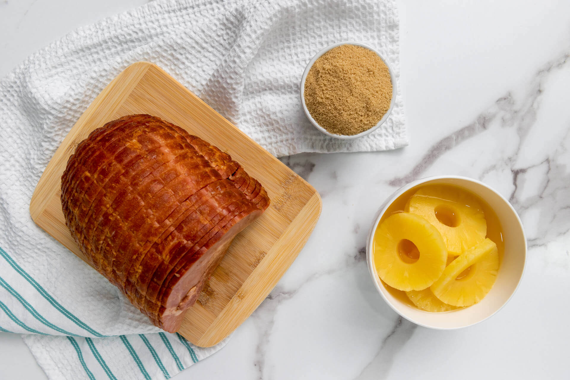 A ham on a cutting board with brown sugar and pineapple.