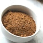 A small white bowl of seasoning sits on a marble surface.