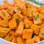A white bowl of savory roasted sweet potatoes with rosemary.